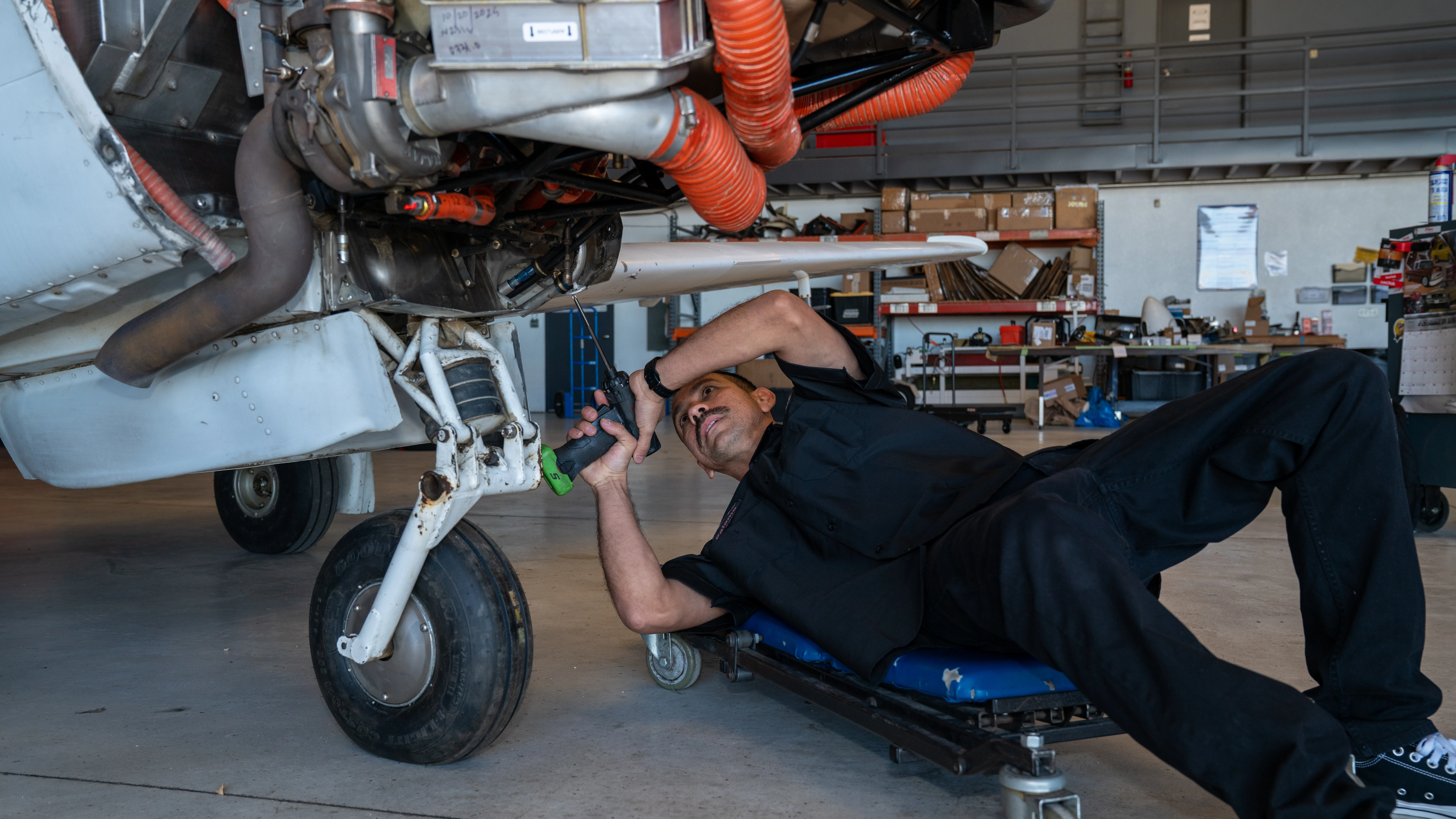Specialized technician performing under-aircraft repairs at MH Aviation at Lancaster, California