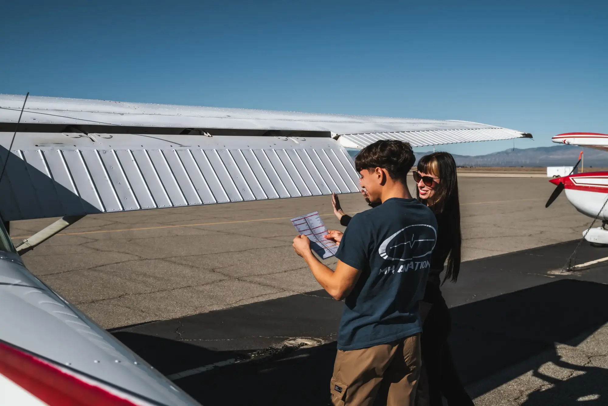 Certified Flight Instructor holding checklist with private pilot student inside cockpit at Lancaster, CA
